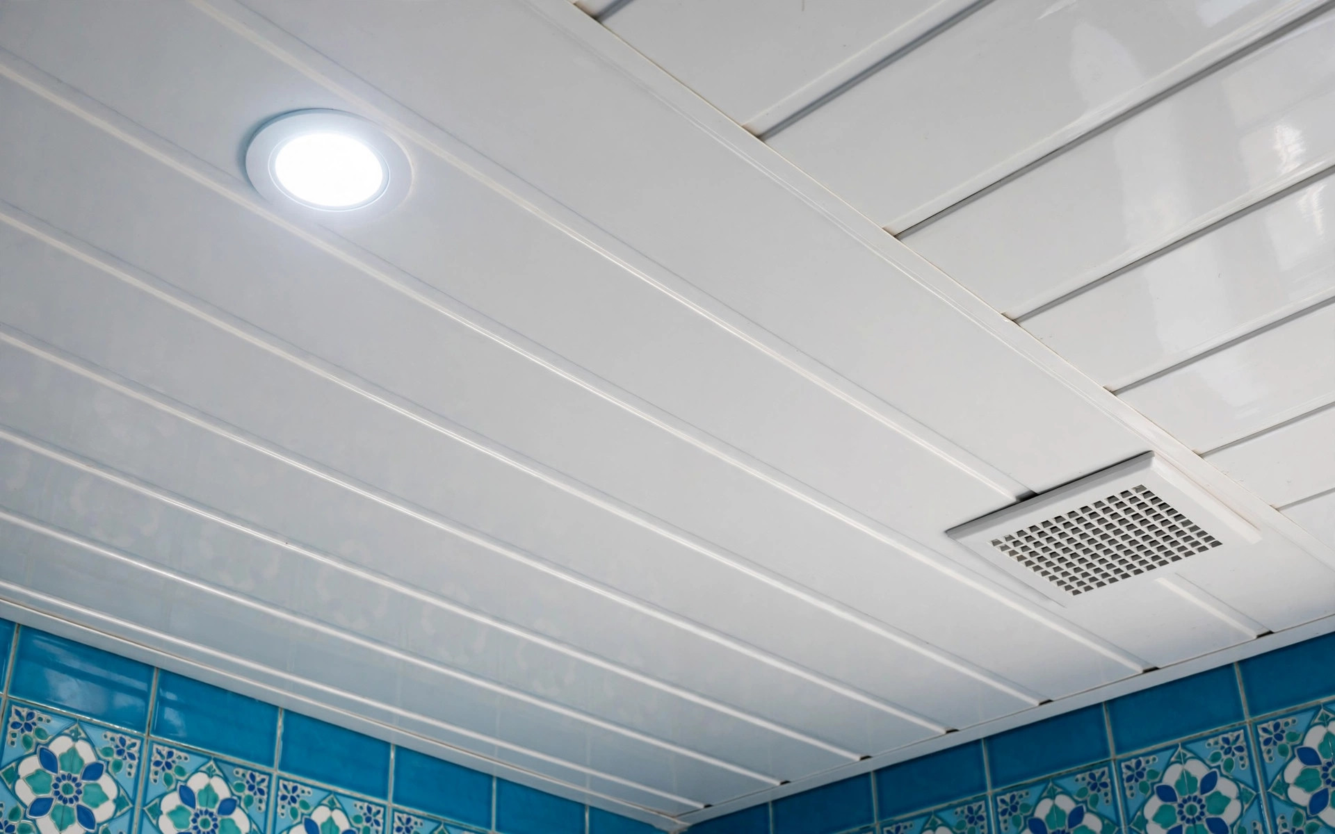 Close-up concept render of a glossy white PVC panel false ceiling with a recessed LED light and exhaust grille