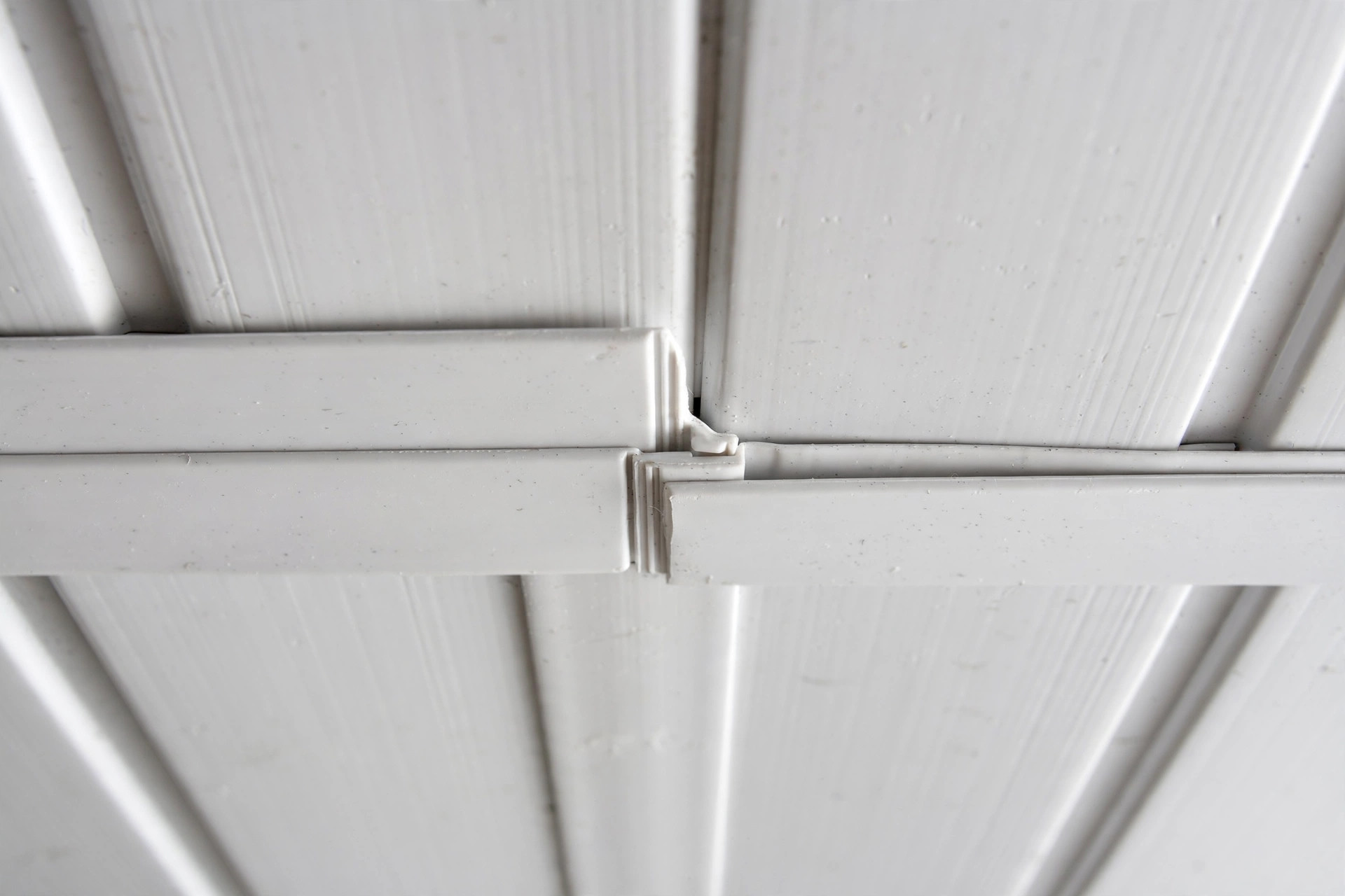 Close-up of interlocking PVC panel joints on a hall ceiling