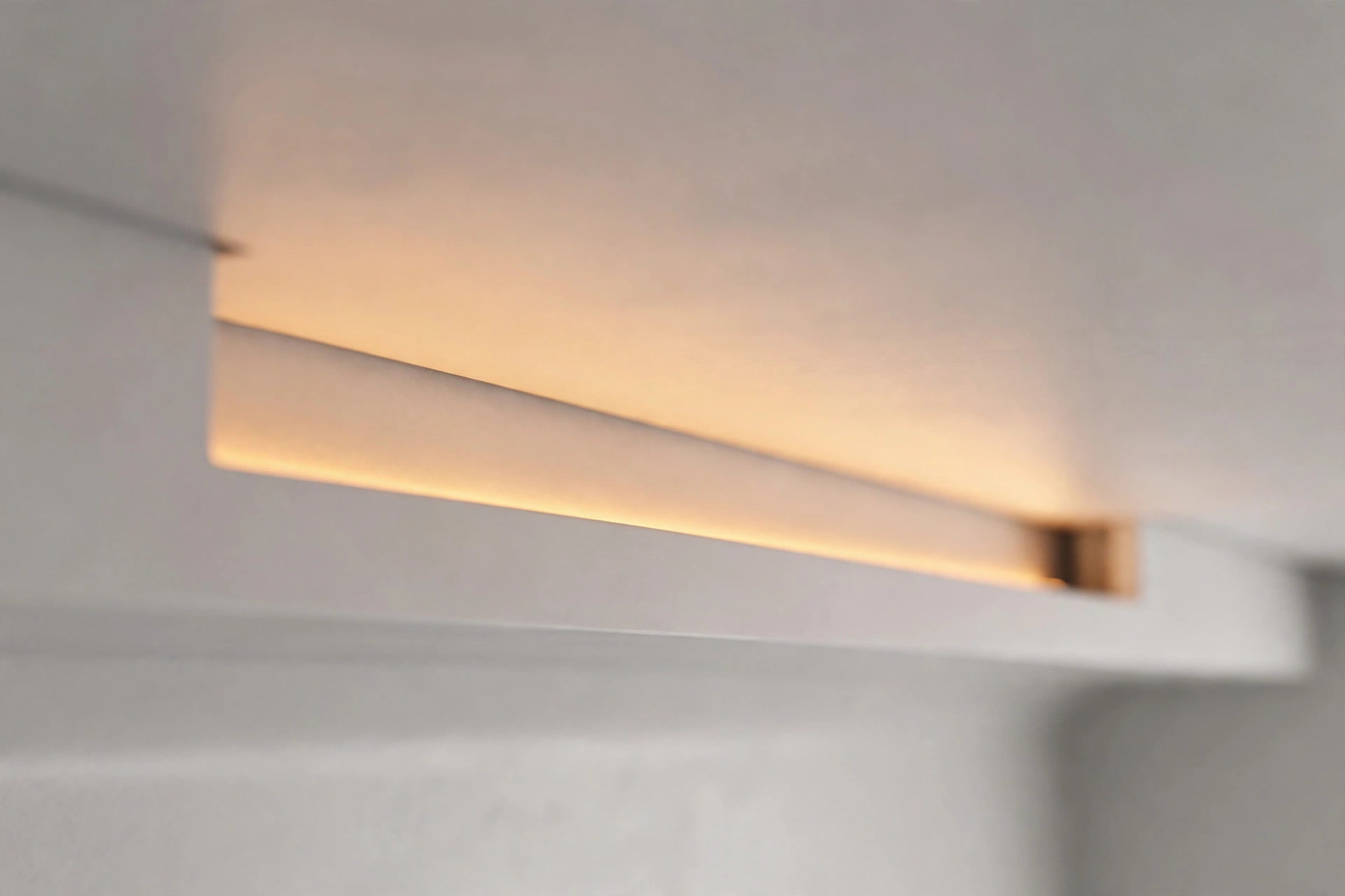Close-up of a slim false-ceiling cove trough with a concealed warm LED strip washing light onto the ceiling