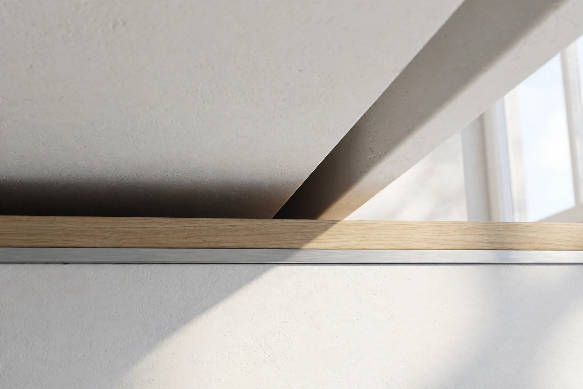 Close-up of a ceiling corner where matte white gypsum meets a thin band of light wood and a slim metal trim line