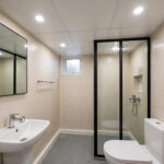 Small bathroom with a flat white PVC panel false ceiling and recessed lights