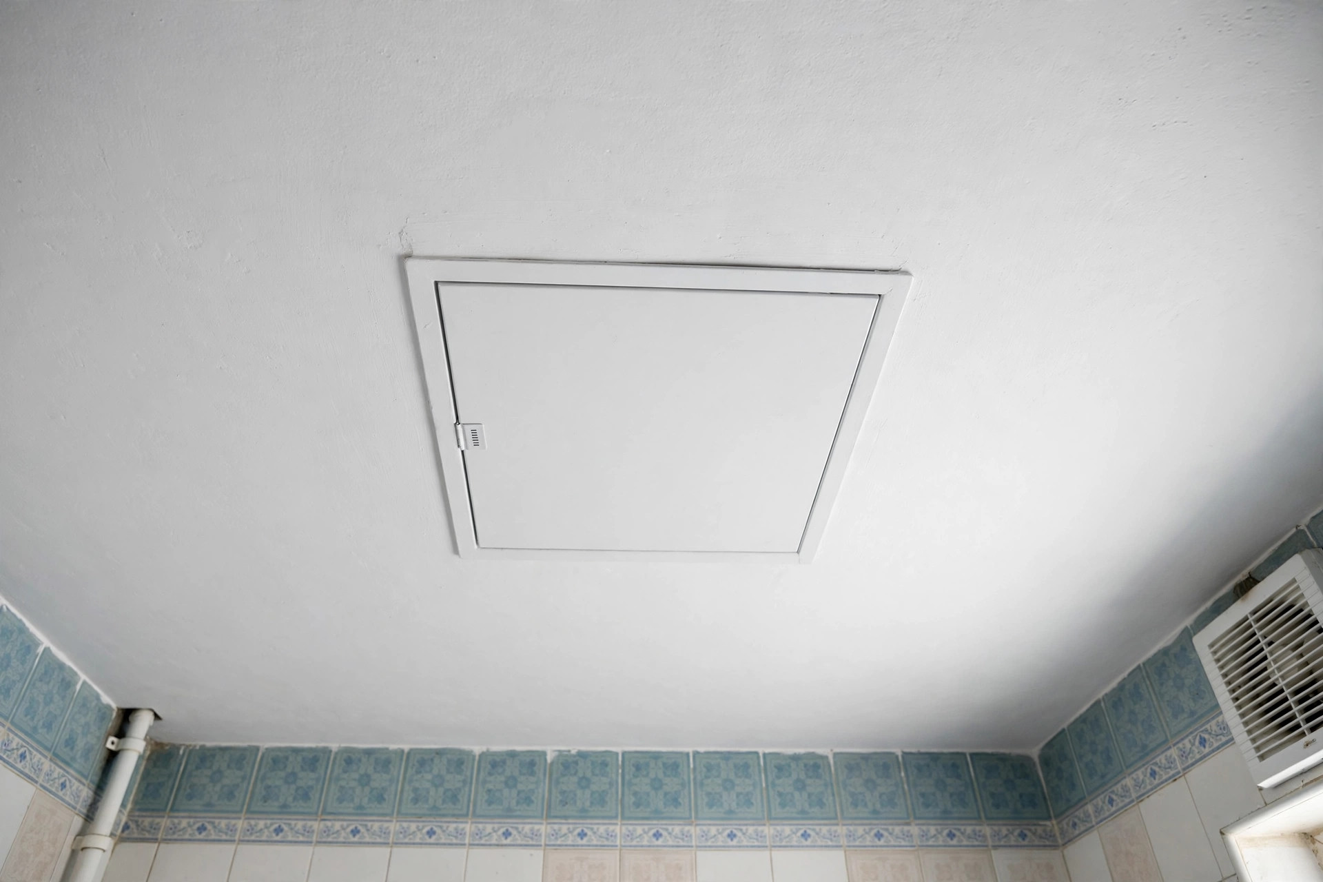 Bathroom ceiling with a flush access panel for plumbing