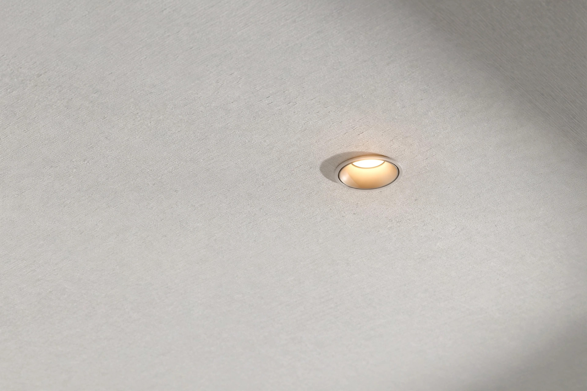 Close-up of a white gypsum ceiling with a subtle linen-like texture and a recessed spotlight