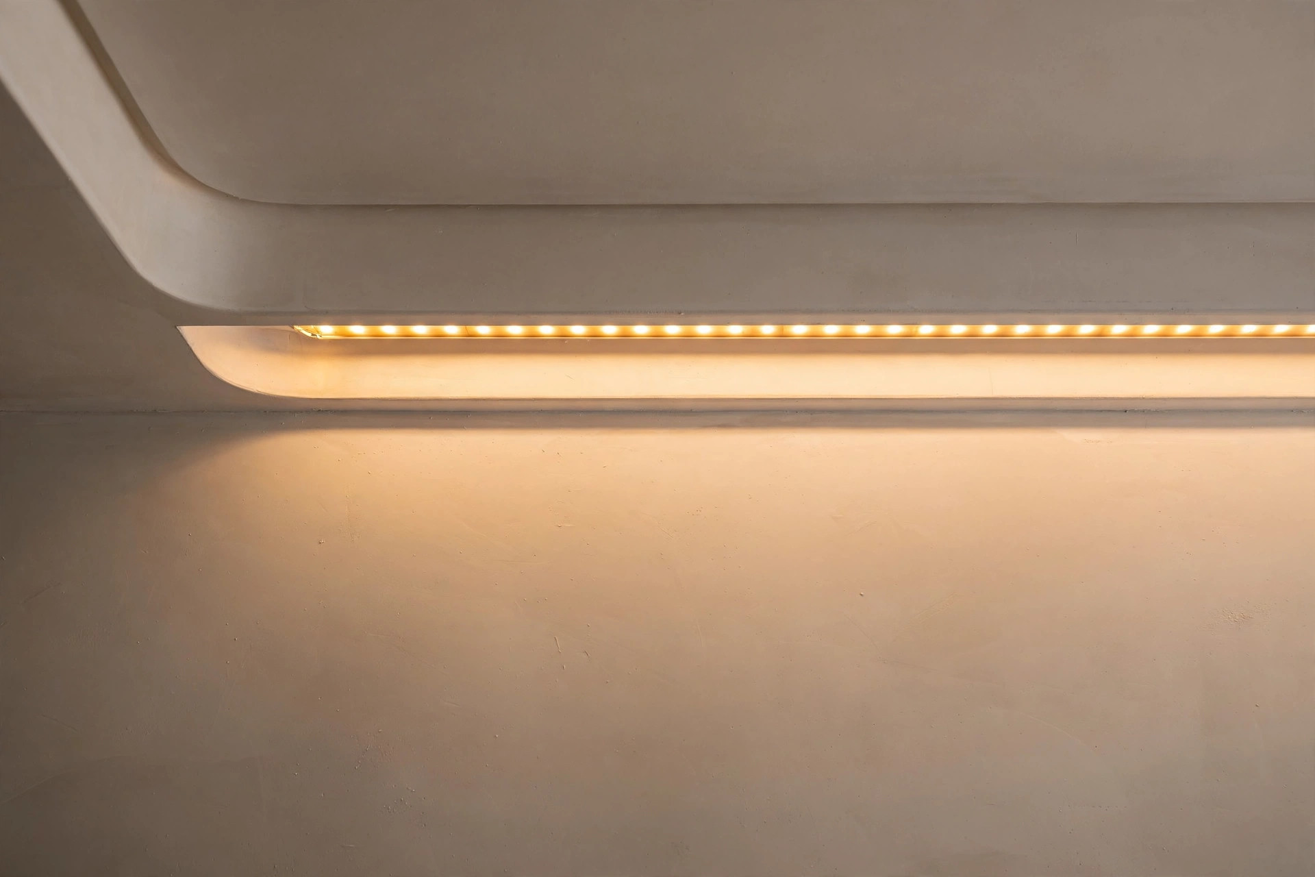 Close-up of a warm LED strip glowing inside a gypsum ceiling cove