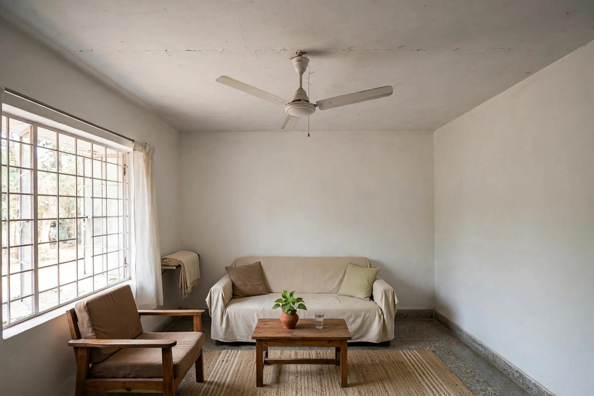 Ceiling fan mounted directly on a plain white slab ceiling in a simple living room