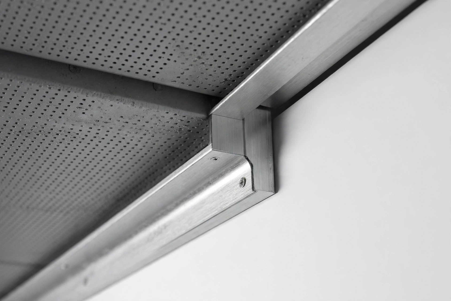 Close-up of aluminium edge trim where metal ceiling tiles meet a wall