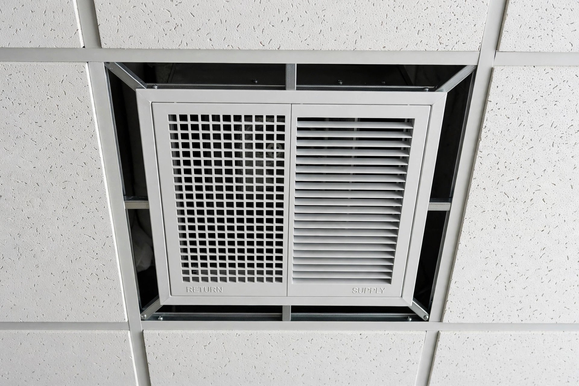 Air-conditioning supply grille fitted into the grid ceiling of an office