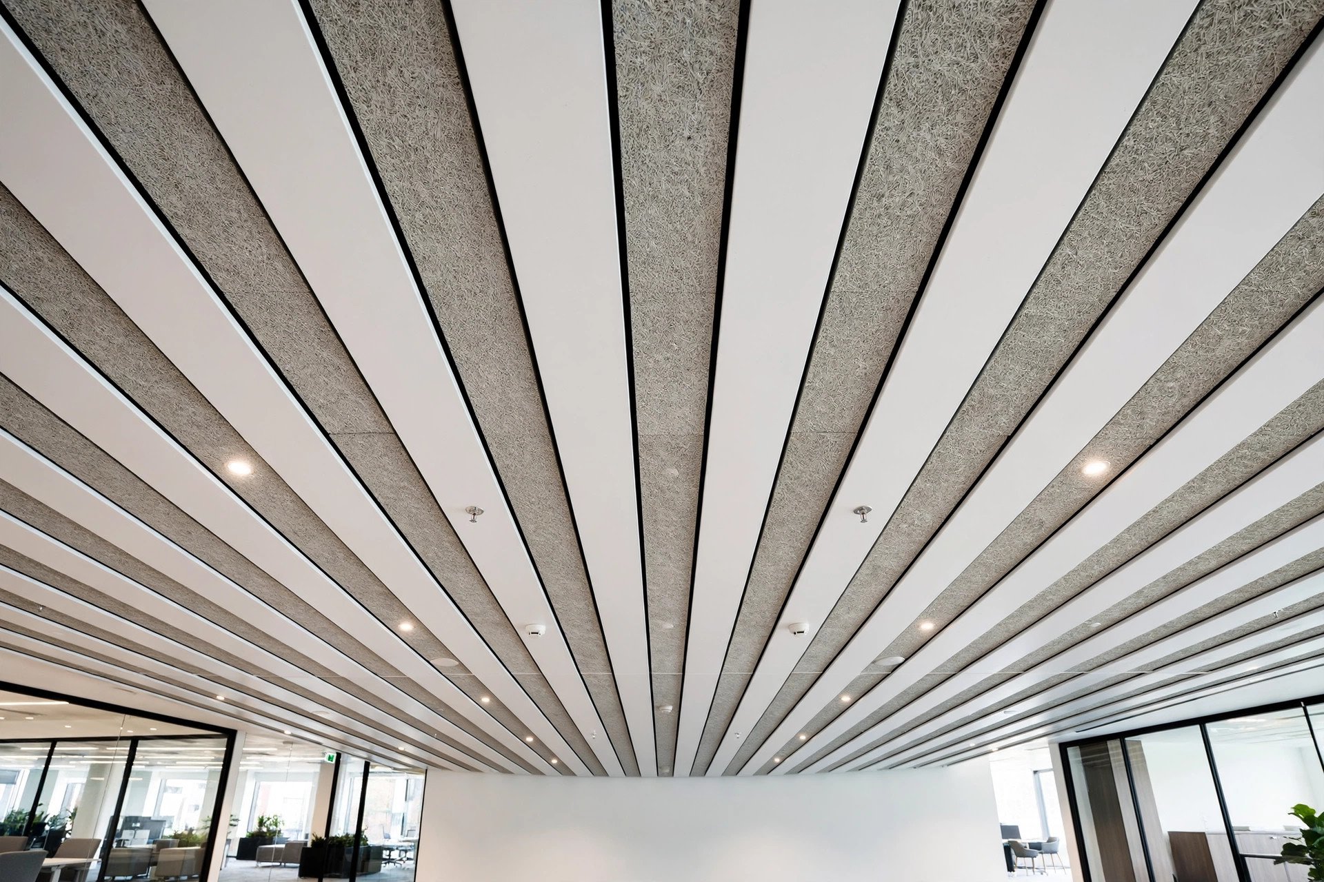Bandraster grid ceiling with wide parallel bands and acoustic infill strips in a corporate office