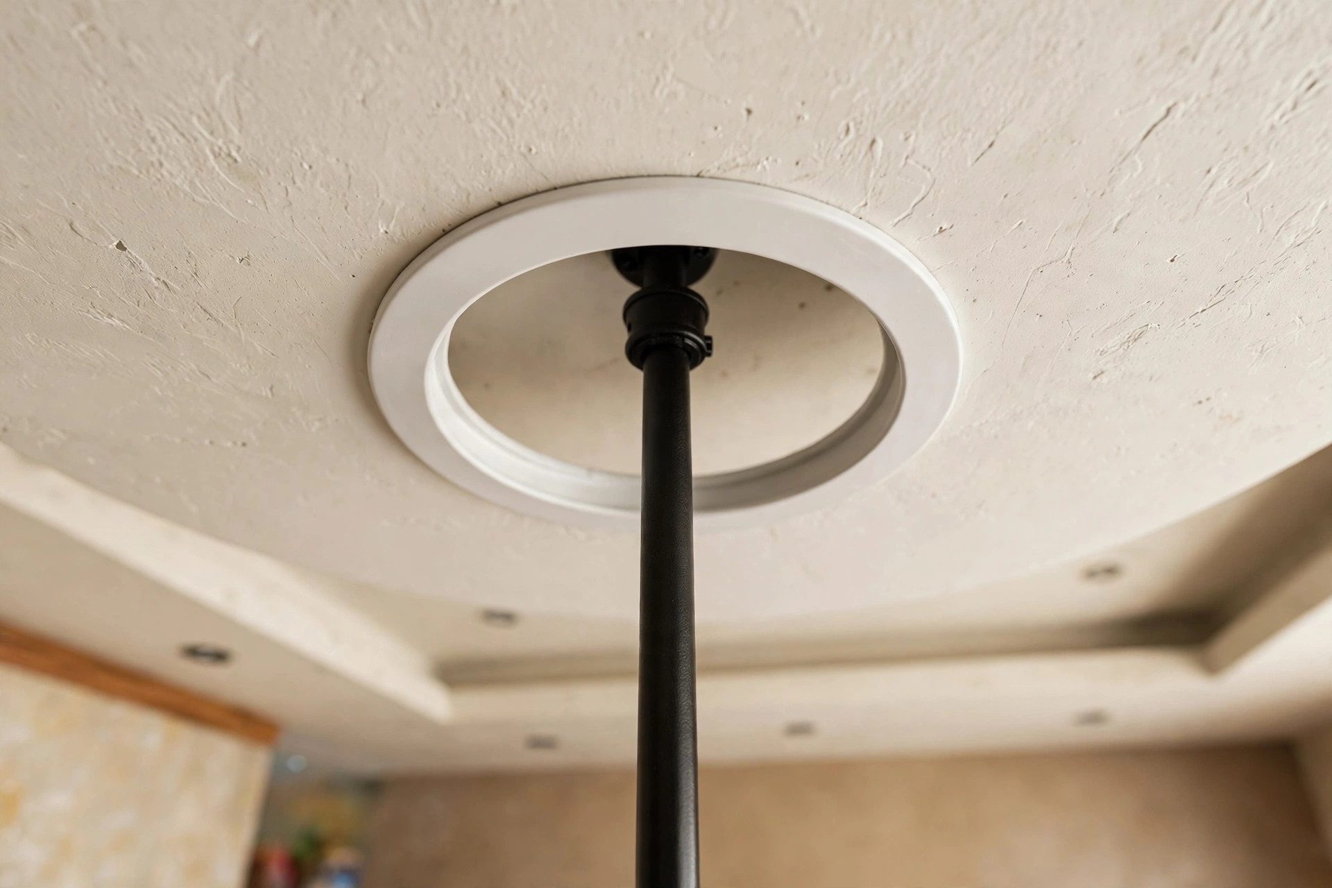 Close-up of a neat circular cutout ring in a false ceiling where a fan downrod passes through