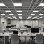 Open-plan office with a grid-tile false ceiling, rows of LED panels and neat workstations below
