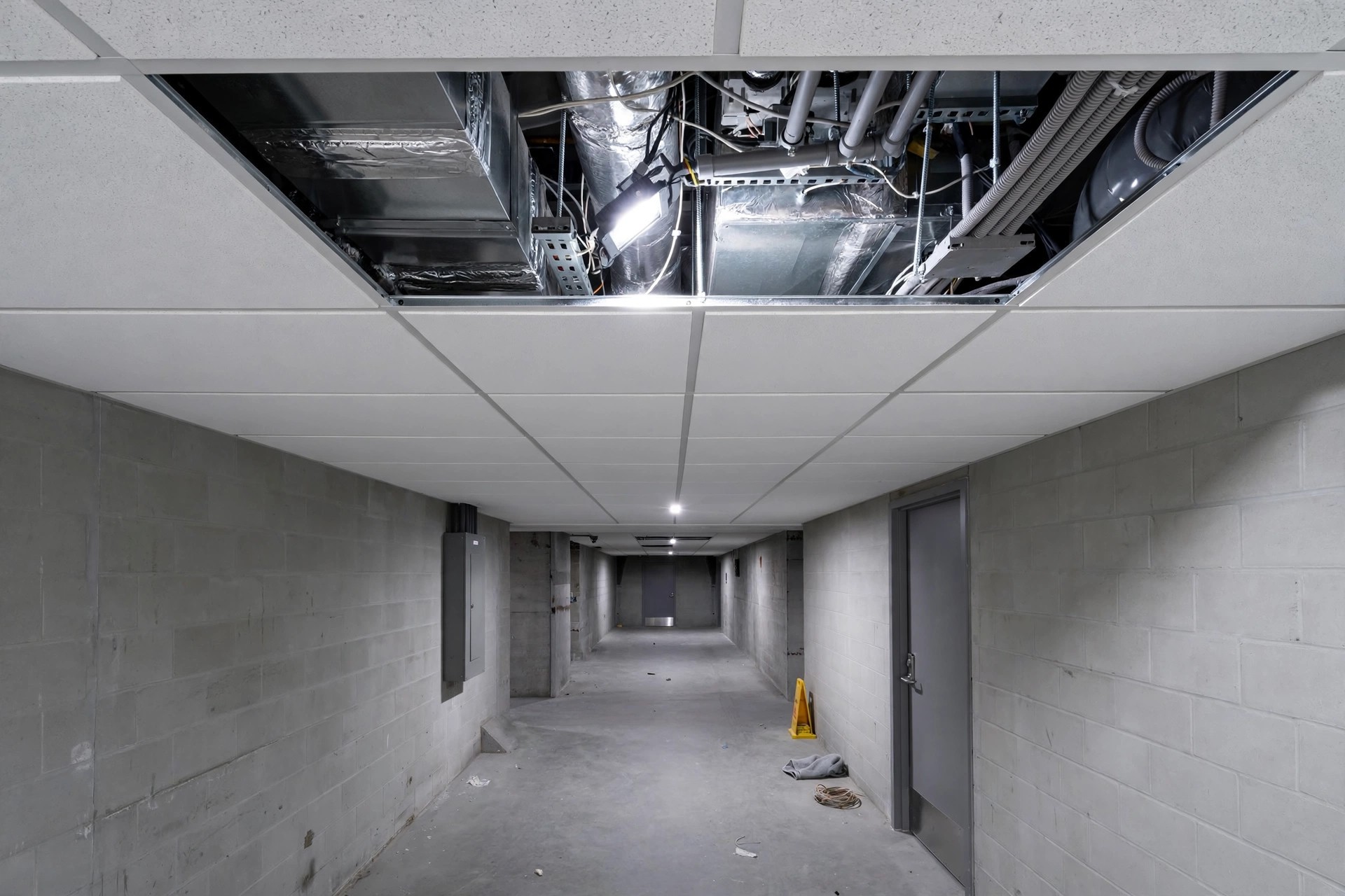 Open access panel in a grid ceiling showing wiring and ducts above for servicing